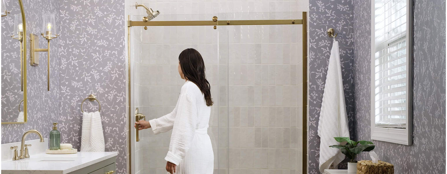 Woman in a white robe opening a glass shower door in a bathroom with decorative elements.