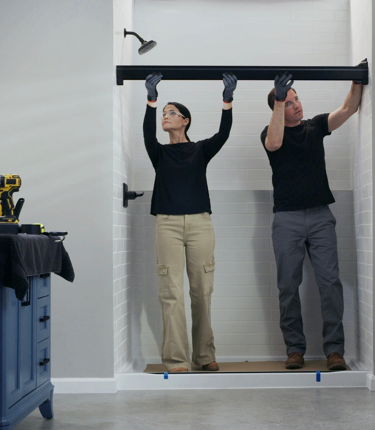 Two people installing a black shower door track